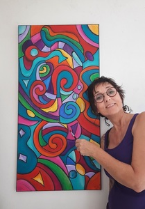 Sofieg artiste devant un de ses tableau très coloré
